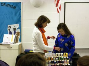 Costume design teacher Ruth Talvacchia helps freshman Annabelle Tocco try on her costume for this year's musical during D-block today as part of a demonstration for the Intro to Costume Design class.