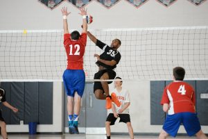 Senior Ezekial Francisco spikes the ball past a defender in a Tiger loss over Natick. Photo by Judith Gisbon-Okunieff