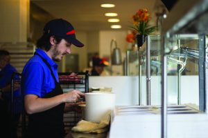 A Chartwells employee serves food to students during third lunch Mondat, Oct. 6.
