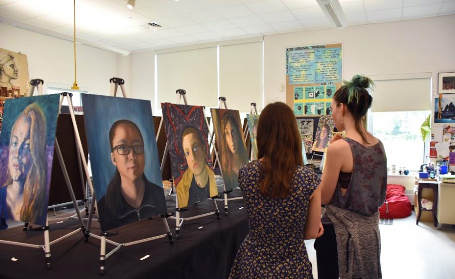 Students admire senior self portraits during Art Morning. (Photo by Lilah Gentry)
