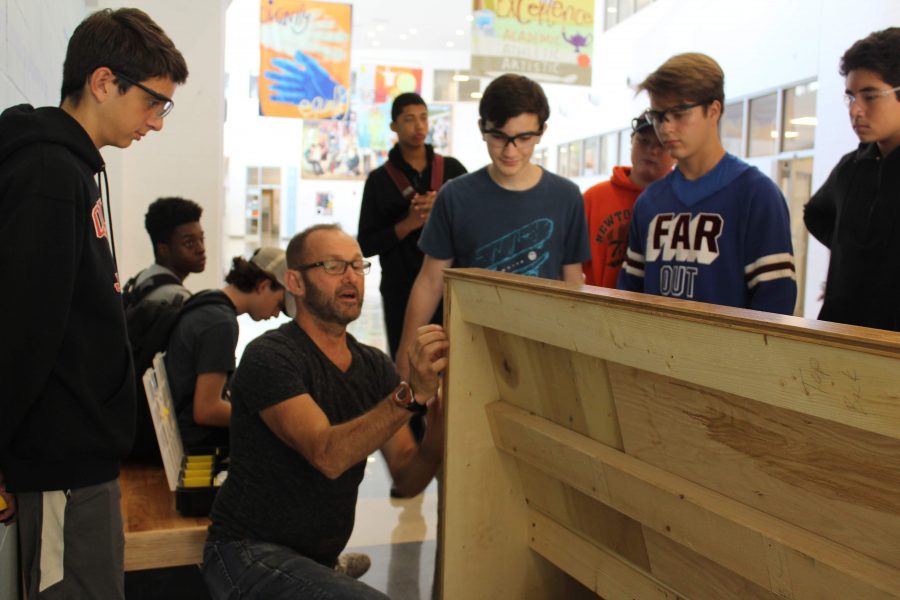 Carpentry teacher Garrett Tingle works with students to install the prototype benches. (Photo by Joelle Sugianto)