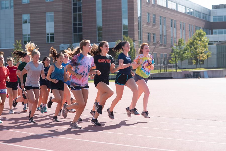 Members of girls cross country practice on the track at Dickinson Stadium.