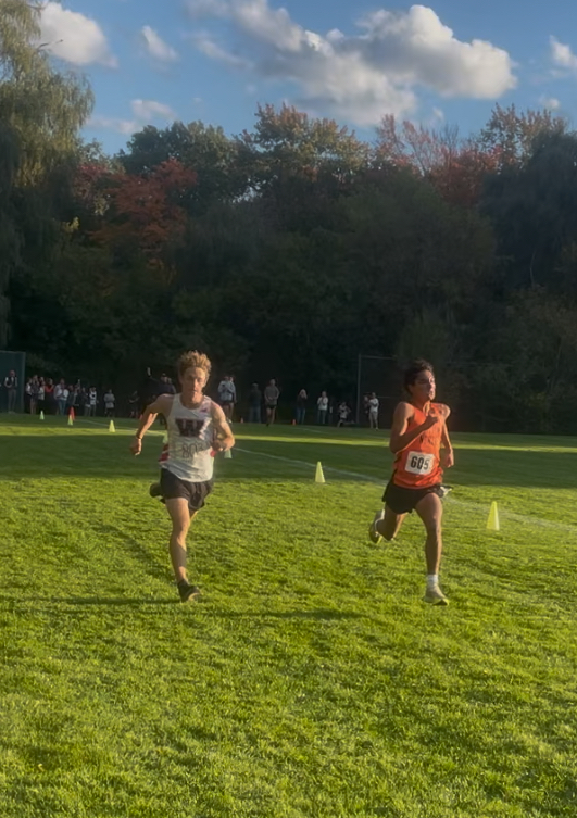 Junior Max Badri strides to the finish line neck and neck with Wellesley opponent Wednesday, Oct. 9. 